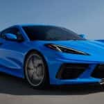 A blue 2022 Chevy Corvette is shown from the side driving on an open road.