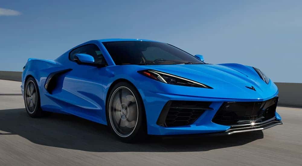 A blue 2022 Chevy Corvette is shown from the side driving on an open road.