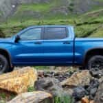 Popular at Houston Chevy truck dealers, a blue 2022 Chevy Silverado ZR2, is shown from the side parked near a grassy hillside.