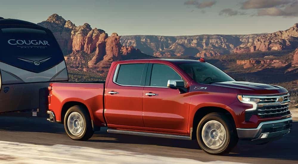 A red 2022 Chevy Silverado 1500 is shown towing a camper trailer aftr leaving a Houston Chevy truck dealer.