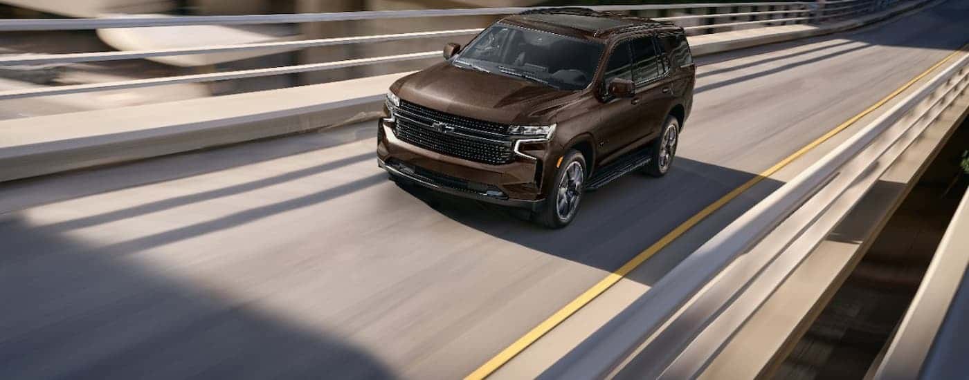A brown 2023 Chevy Tahoe is shown driving on a highway after leaving a Magnolia Chevy dealer