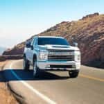 A white 2022 Chevy Silverado 3500HD LTZ is shown driving after leaving a Spring Texas Chevy dealer.