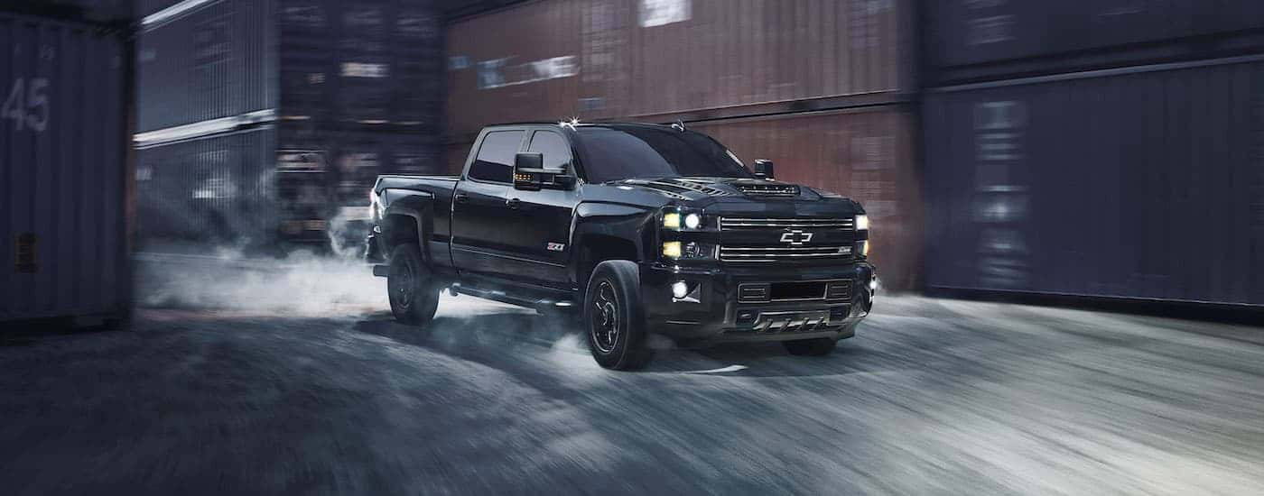 A black 2017 Chevy Silverado 2500HD Z71 is shown driving past shipping containers