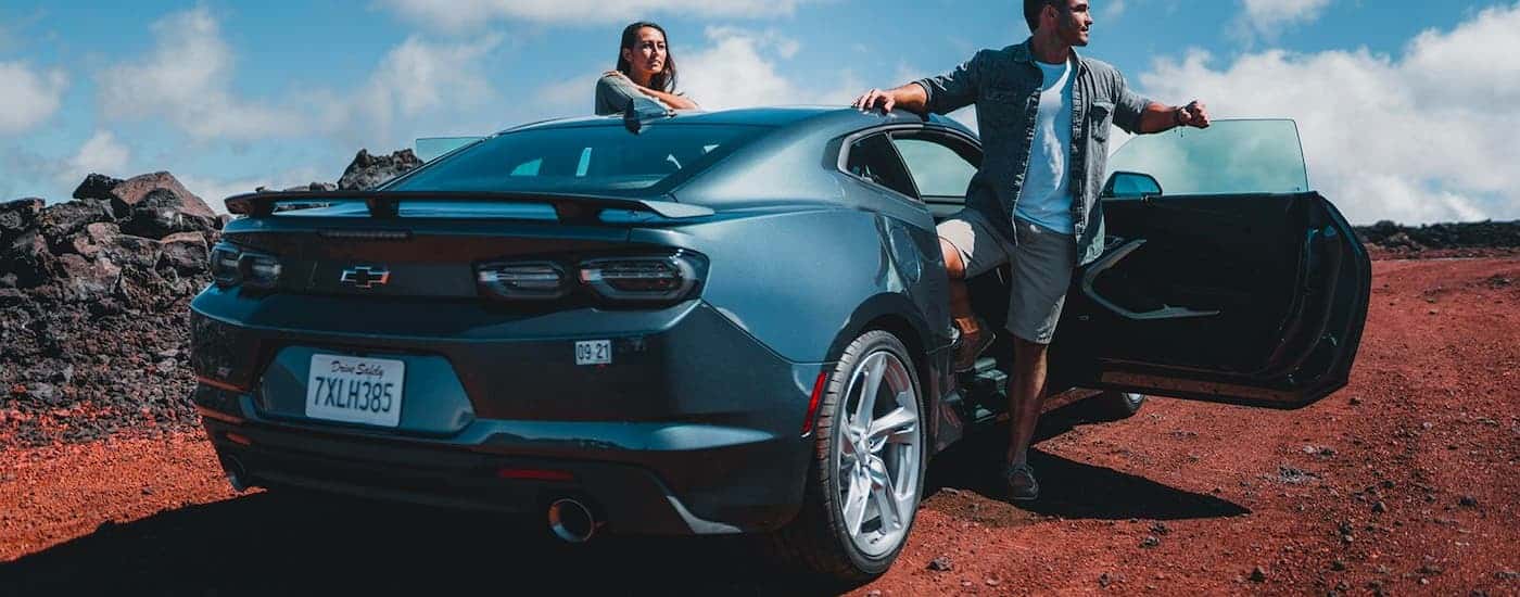 A blue 2021 Chevy Camaro SS is shown from the rear parked on a dirt path