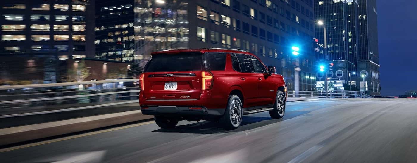 A red 2022 Chevy Tahoe RST is shown from a rear angle driving through a city