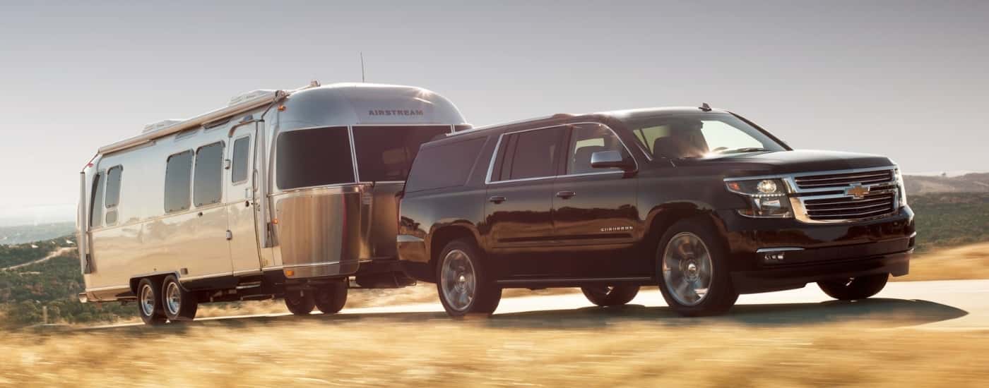 Black 2017 Chevy Suburban towing a trailer to a used Chevy dealer near Houston