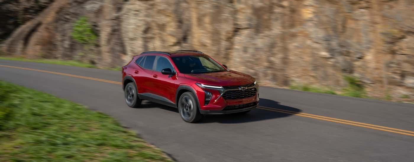 Red 2024 Chevy Trax RS driving past a rockface