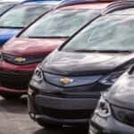 A line of used Chevy EVs, 2017 Bolt EVs, are in a parking lot.