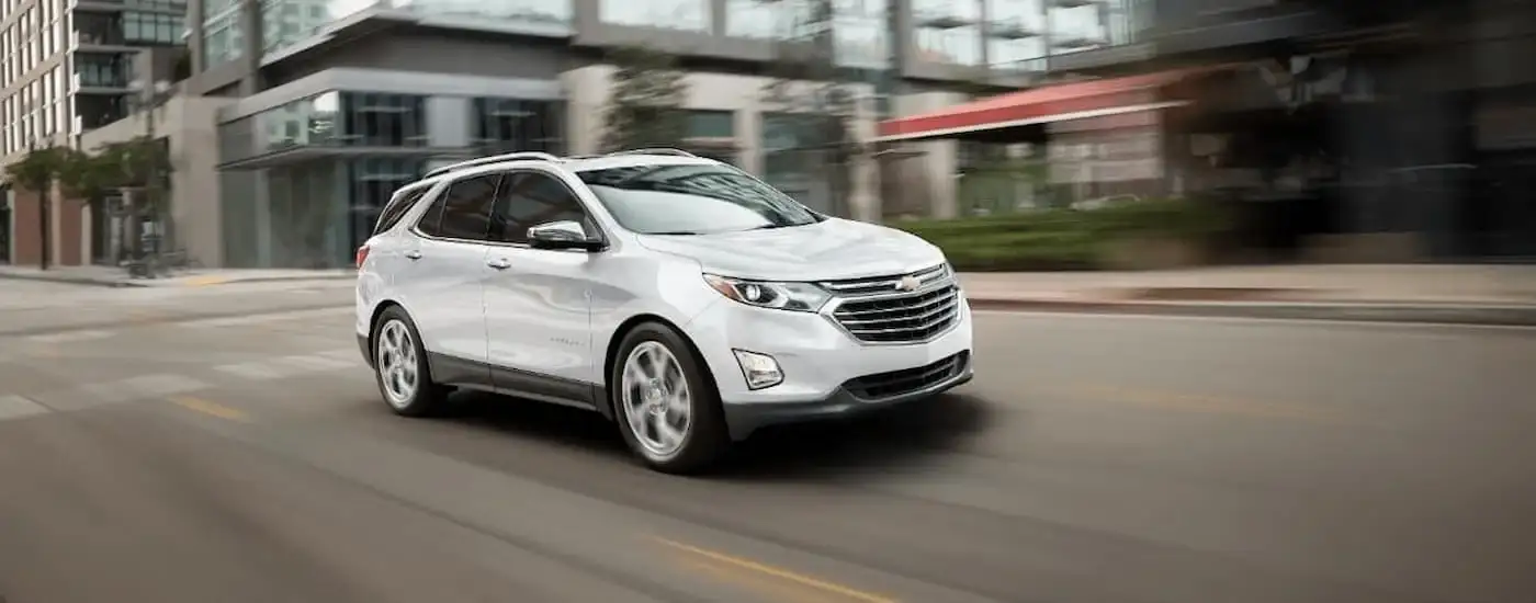 A white 2018 Chevy Equinox is shown driving on a city street.
