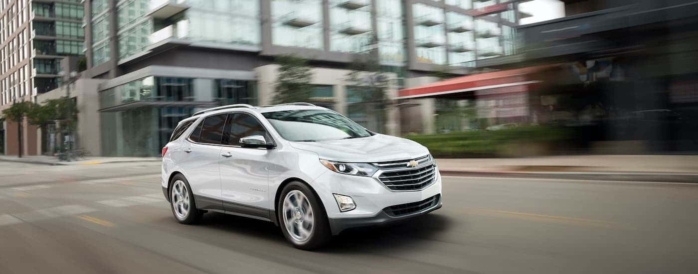 A white 2019 Chevy Equinox is shown driving on a city street