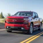A red 2020 Chevy Silverado 1500 is shown driving on an open road.
