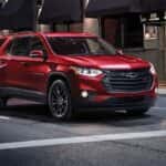 A red 2019 Chevy Traverse is driving through a city at night after searching for used car dealer near me.