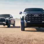 A 2023 Toyota Tundra Platinum Edition driving next to a 1974 Edition