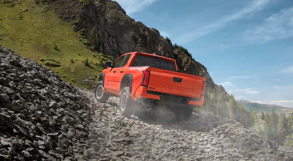 Orange 2024 Toyota Tacoma TRD driving on rocks