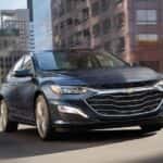 Blue 2022 Chevy Malibu from the front at an angle driving down the road.