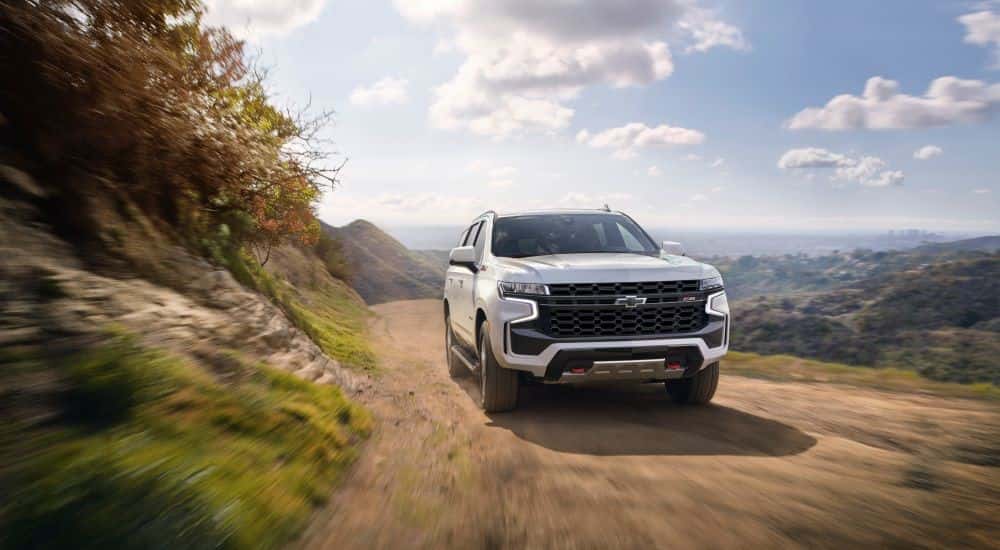 A white 2021 Chevy Tahoe driving on a dirt road.