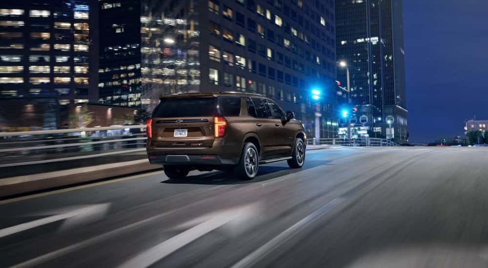 A brown 2021 Chevy Tahoe for sale near Houston is driving in a city.
