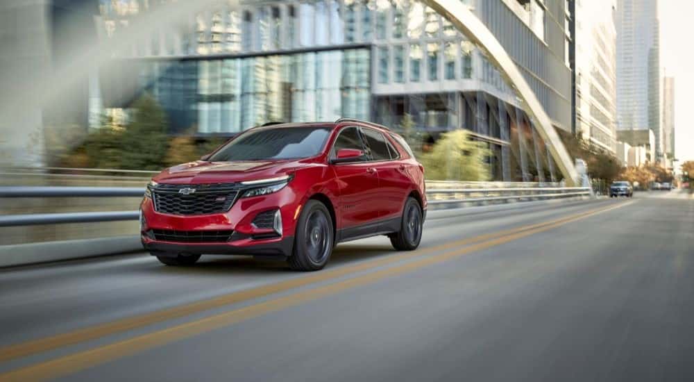 A red 2024 Chevy Equinox RS driving on a city street