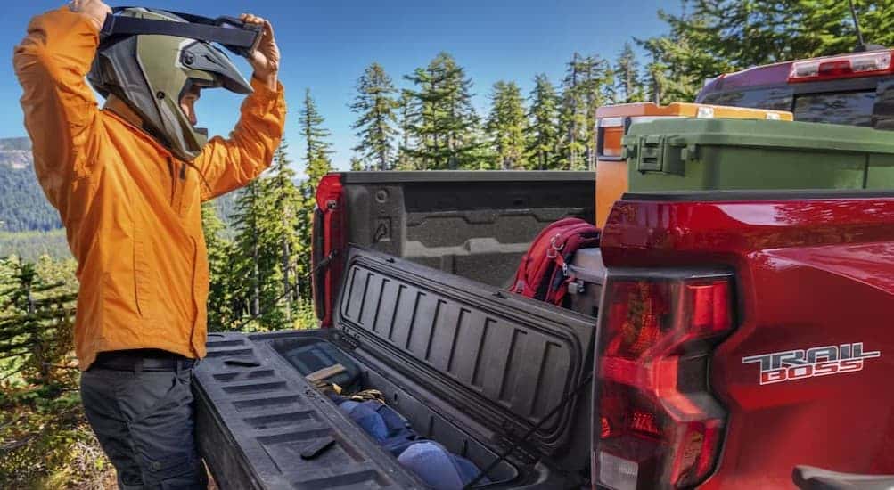 A person standing near the bed of a red 2026 Chevy Colorado Trail Boss.