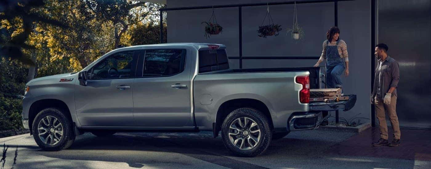 A silver 2025 Chevy Silverado 1500 LT with a couple unloading the bed of their truck
