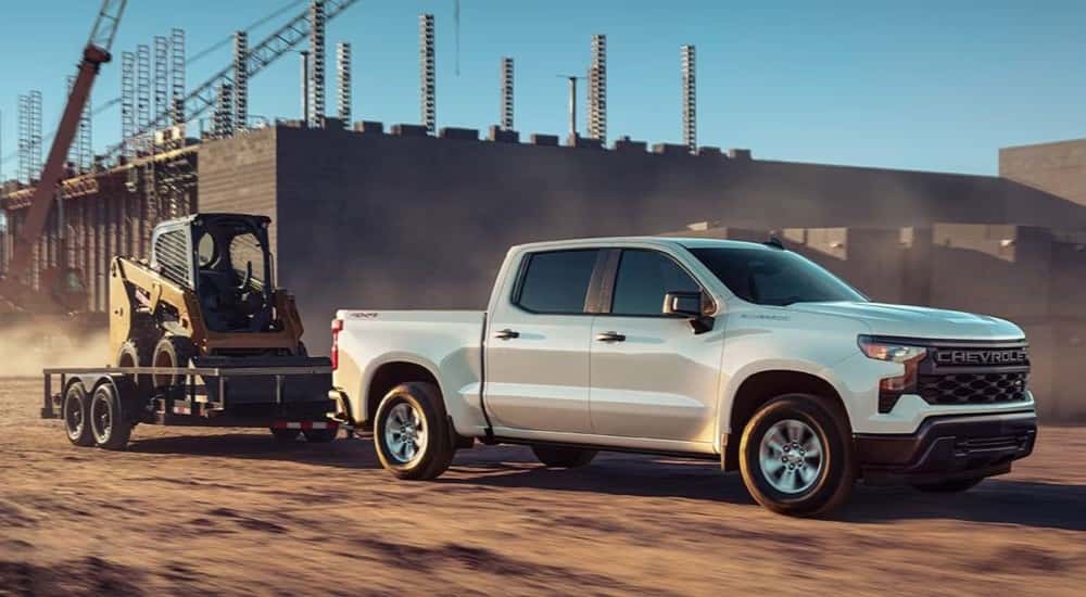 A white 2026 Chevrolet Silverado 1500 WT towing a trailer.