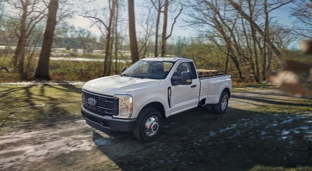 A white 2023 Ford F-350 driving on a dirt trail.