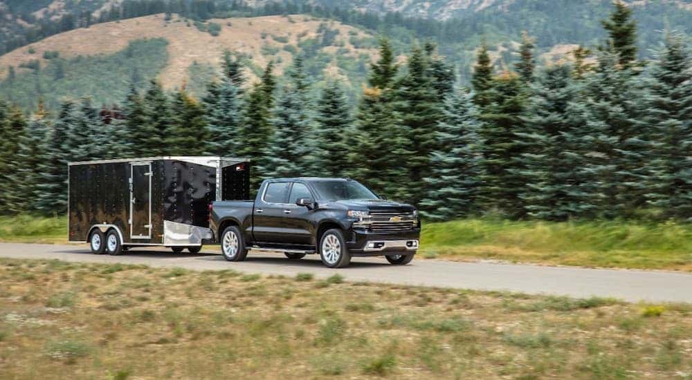 Black 2020 Chevy Silverado 1500 towing a trailer through the forest