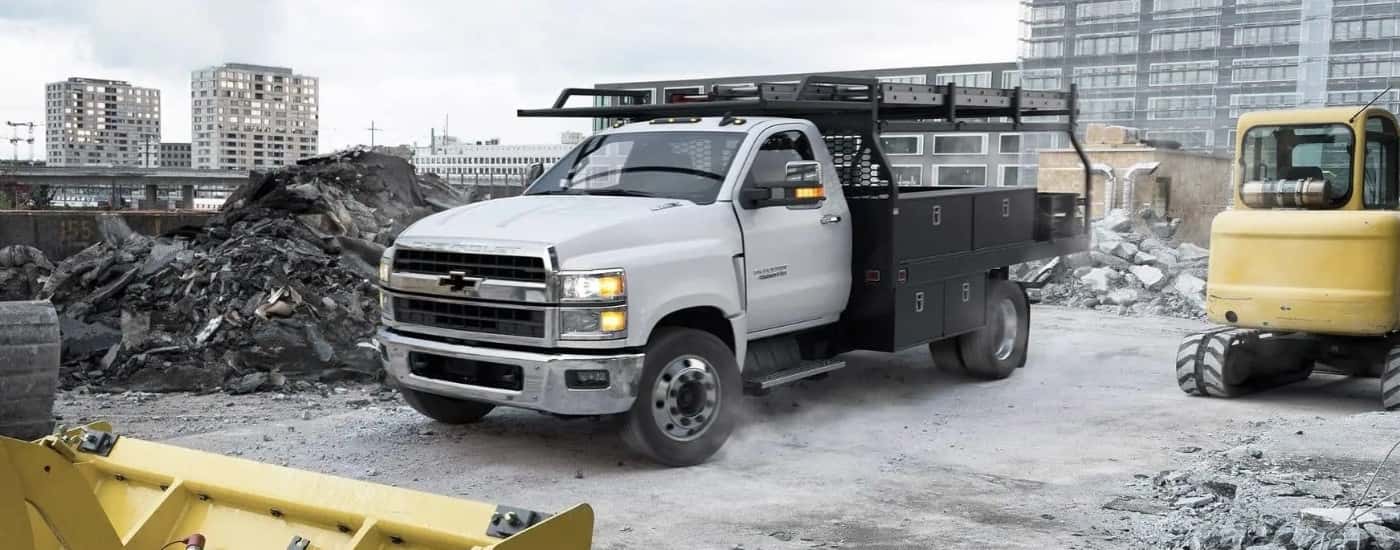 White 2024 Chevy Silverado 4500 HD running with lights on in a debris site