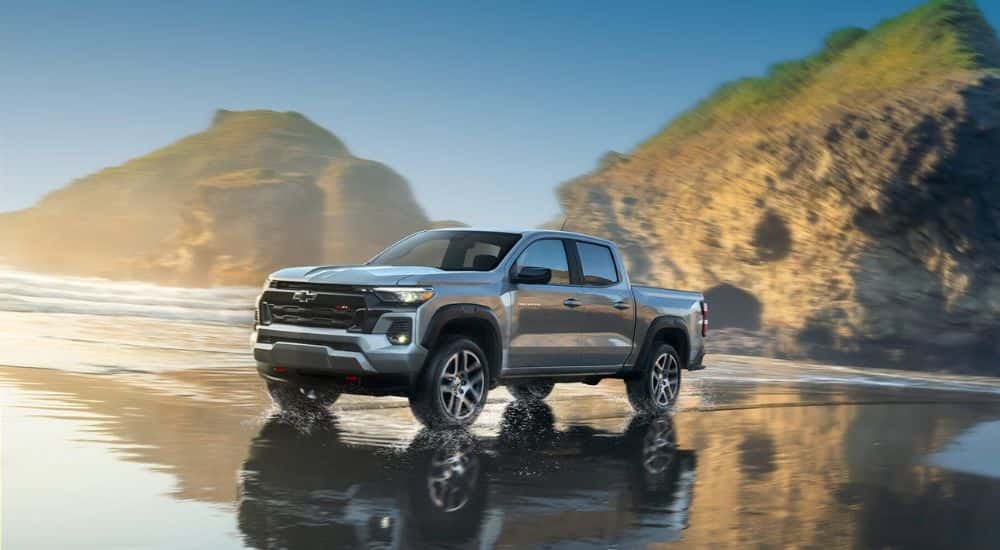 A silver 2023 Chevy Colorado driving on a beach shoreline.
