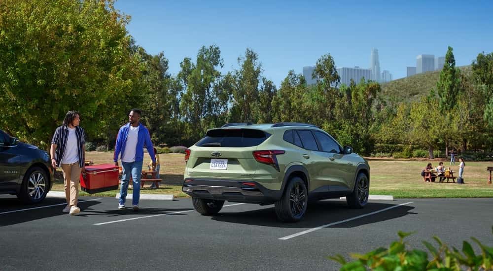 A green 2026 Chevy Trax ACTIV parked next to two people holding a cooler.