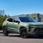 A few people walking towards their green 2026 Chevy Trax.