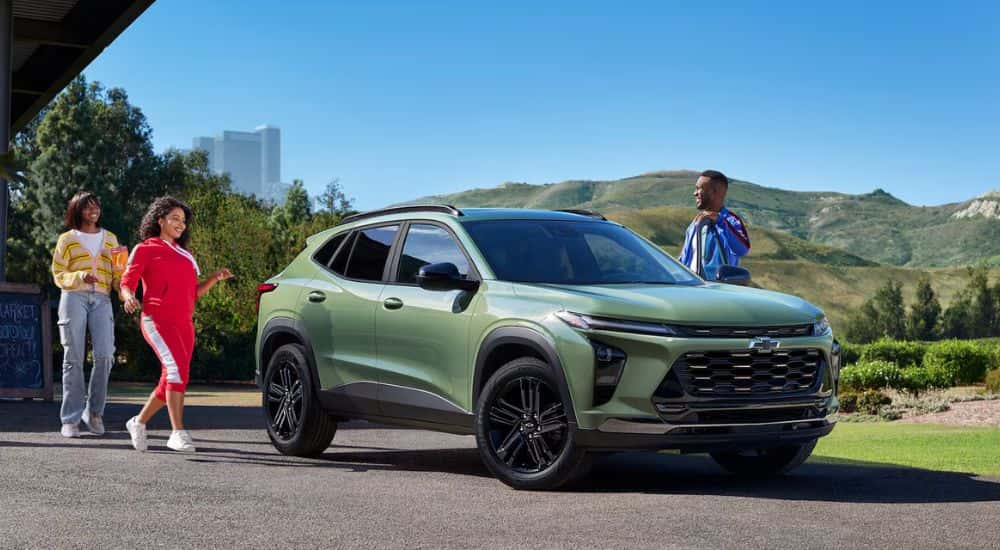 A few people walking towards their green 2026 Chevy Trax.