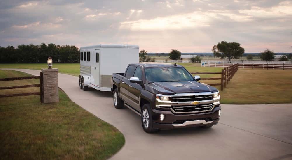 A black 2016 Chevy Silverado 1500 towing a horse trailer.