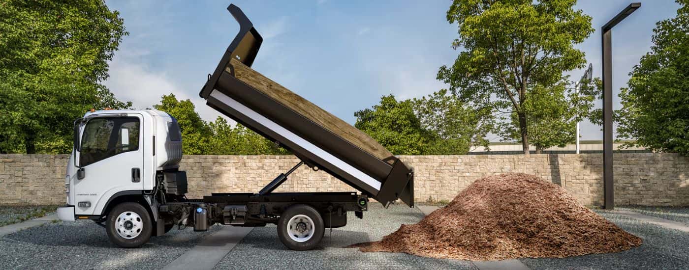 A white 2026 Chevy 4500 HD Low Cab Forward truck dumping mulch.
