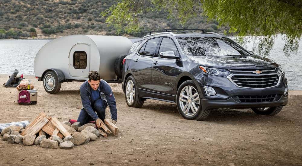Black 2020 Chevy Equinox with a camper parked at a campsite.