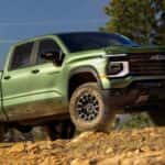 Green 2027 Chevy Silverado 1500 driving on an off-road dirt trail.