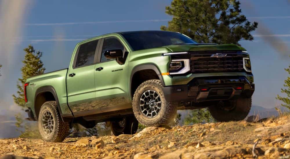Green 2027 Chevy Silverado 1500 driving on an off-road dirt trail.