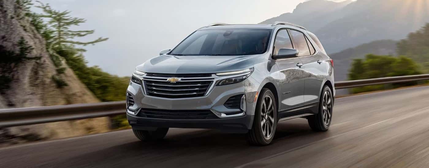 A silver 2023 Chevy Equinox driving by mountains.