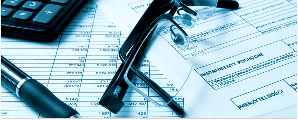 Eyeglasses, a pen, and a calculator resting on financial documents and contract paperwork.
