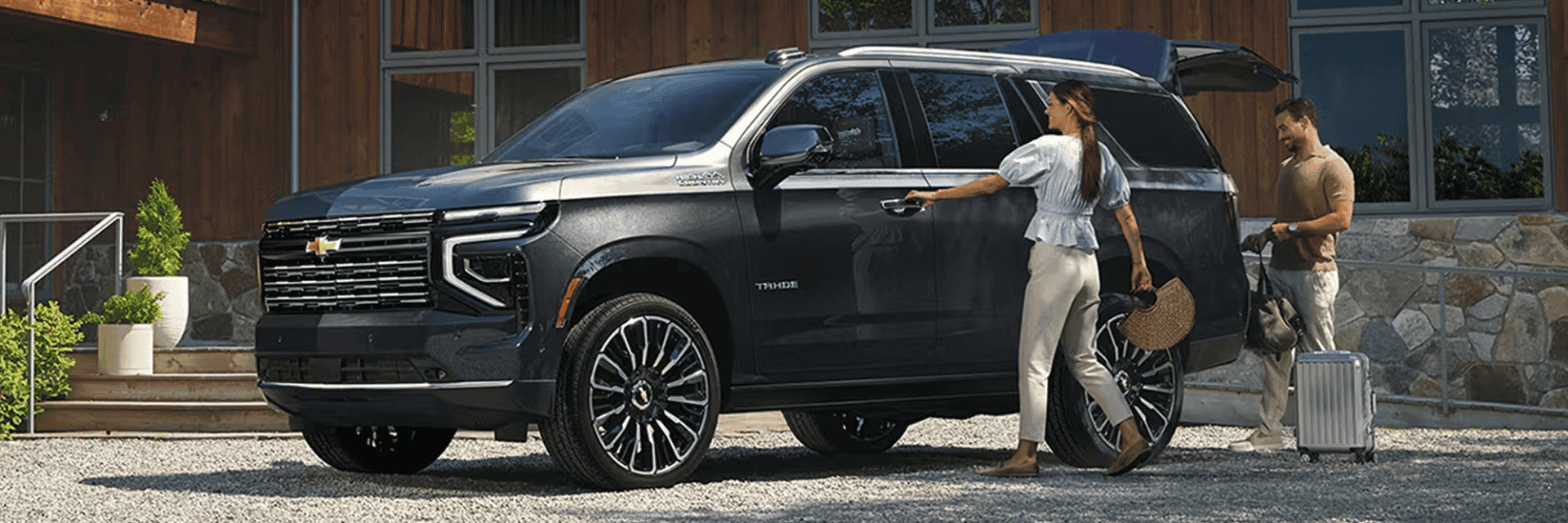 Man and woman next to a parked Chevrolet Tahoe