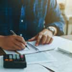 Man doing finances and calculate about cost to real estate investment and in other, tax system.Time for Taxes Money Financial Accounting Taxation Concept
