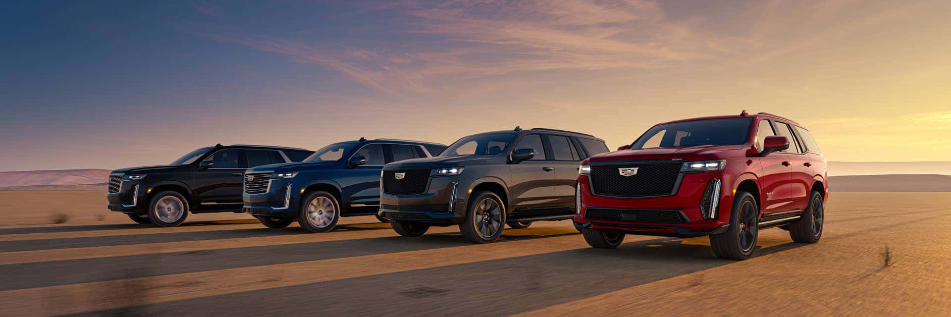 2024 Cadillac Escalade four lined up with the sun to their back and casting long shadows across the desert floor