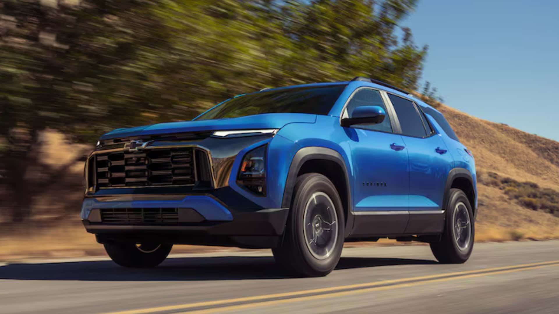 2026 Chevrolet Equinox ACTIV blue SUV front three-quarter view driving on a sunny mountain road.