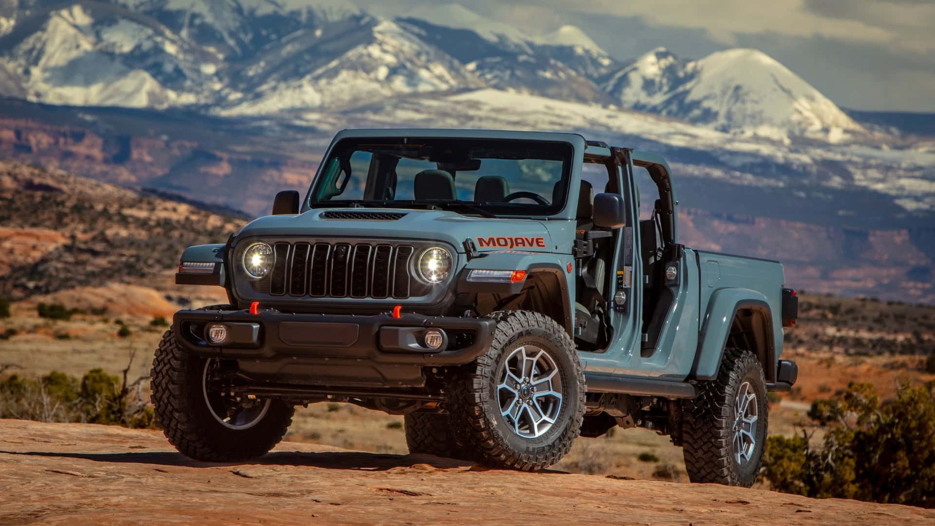 2026 Jeep® Gladiator Mojave blue pickup parked off-road with rugged mountain landscape in the background.