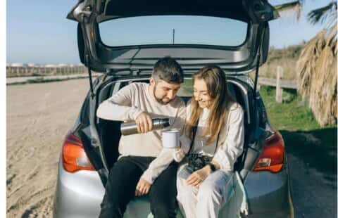 Couple relaxing at the open trunk of their car on a road trip