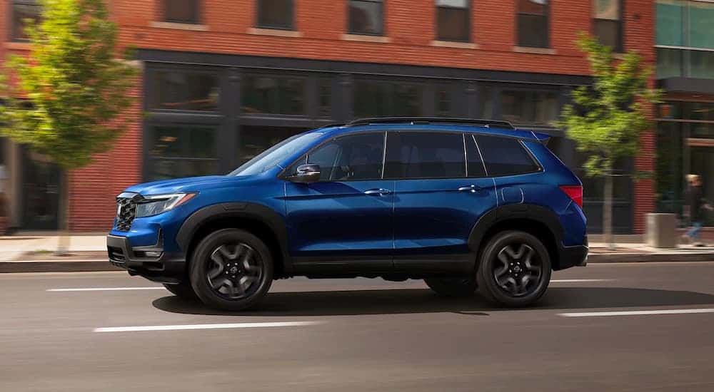 Blue 2023 Honda Passport Elite driving on a city street