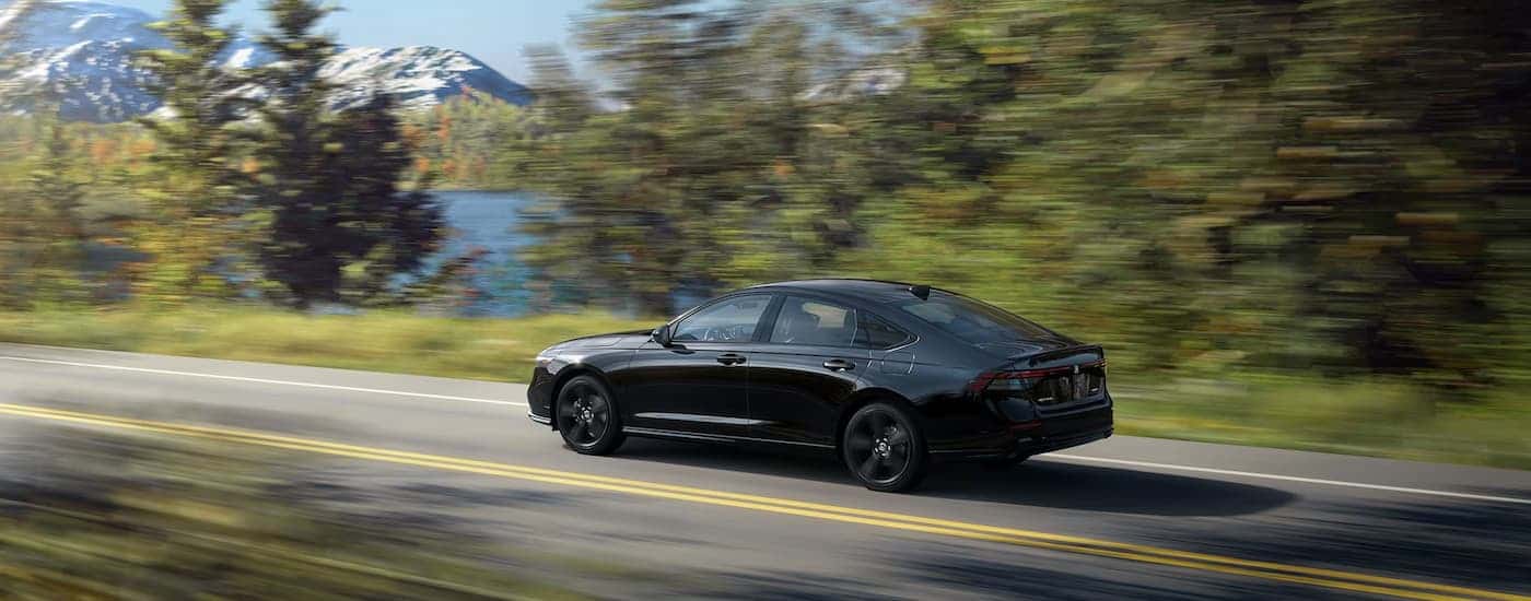 Rear of a black 2023 Honda Accord Sport L driving down a road.