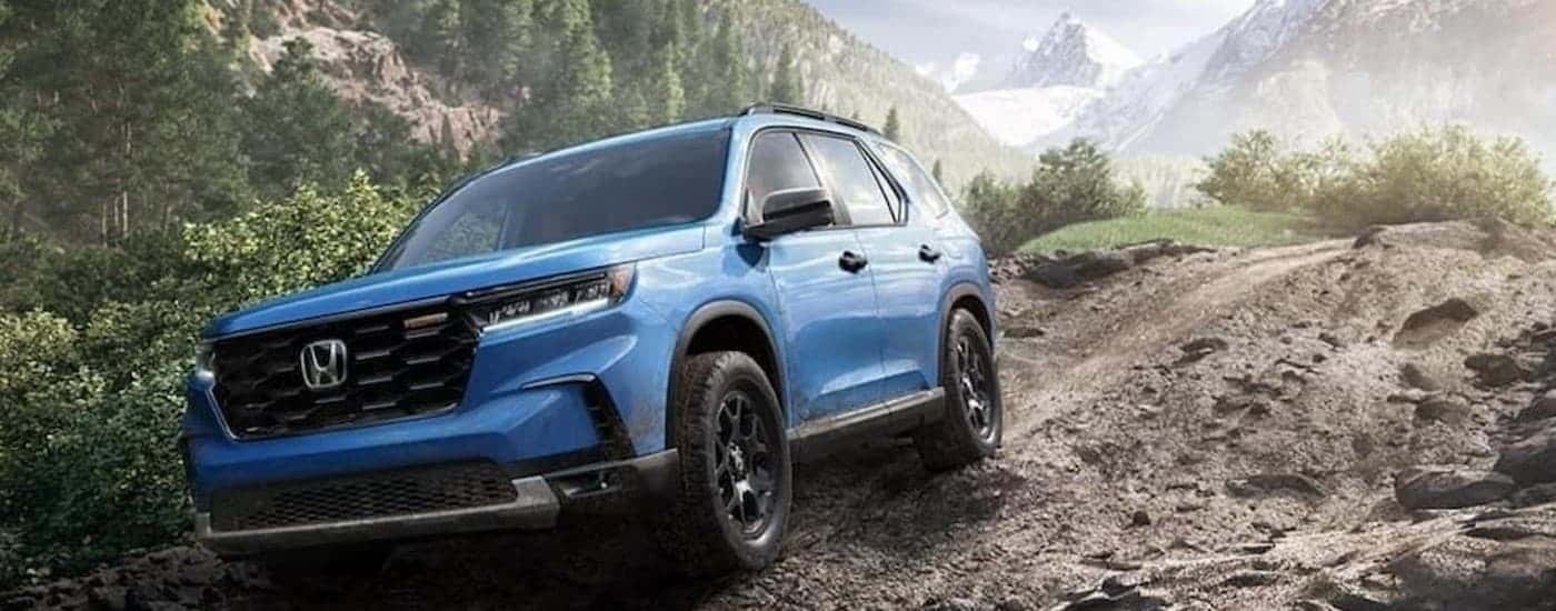 A blue 2024 Honda Pilot TrailSport off-roading.