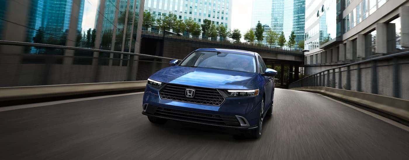 A blue 2025 Honda Accord Touring Hybrid driving in a city