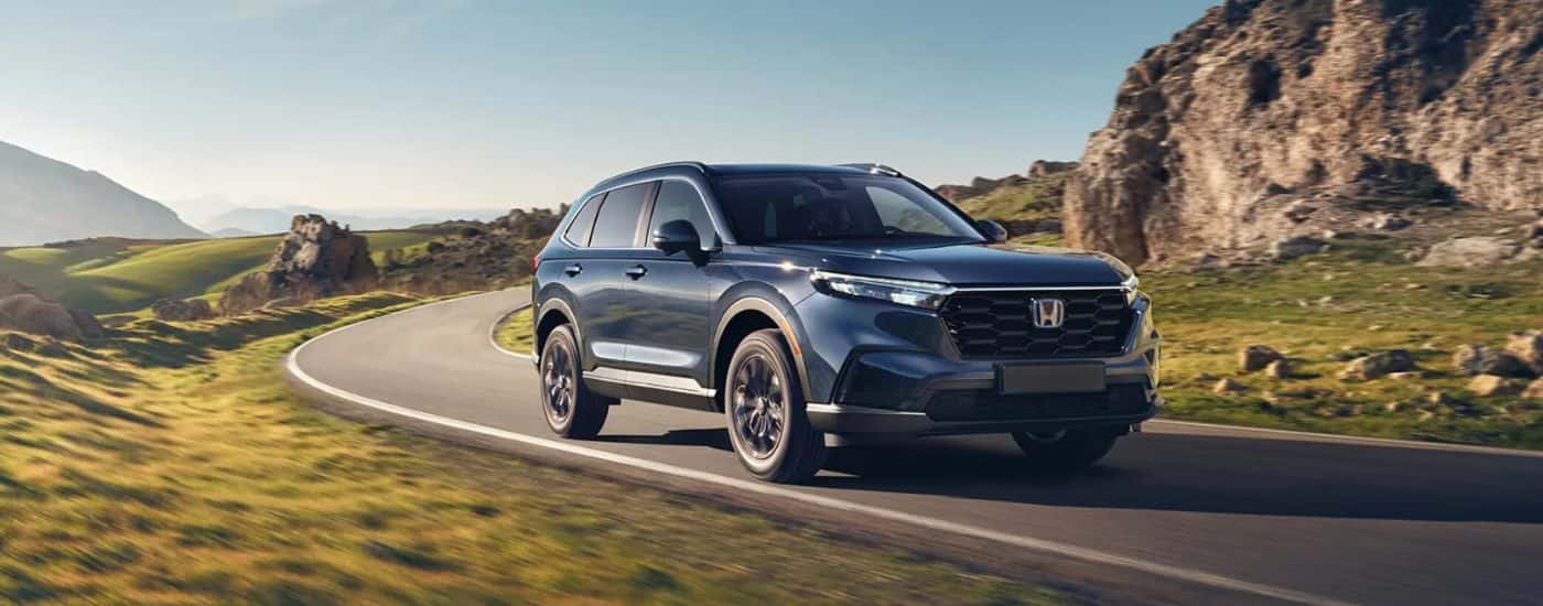 A blue 2025 Honda CR-V driving on a highway for sale